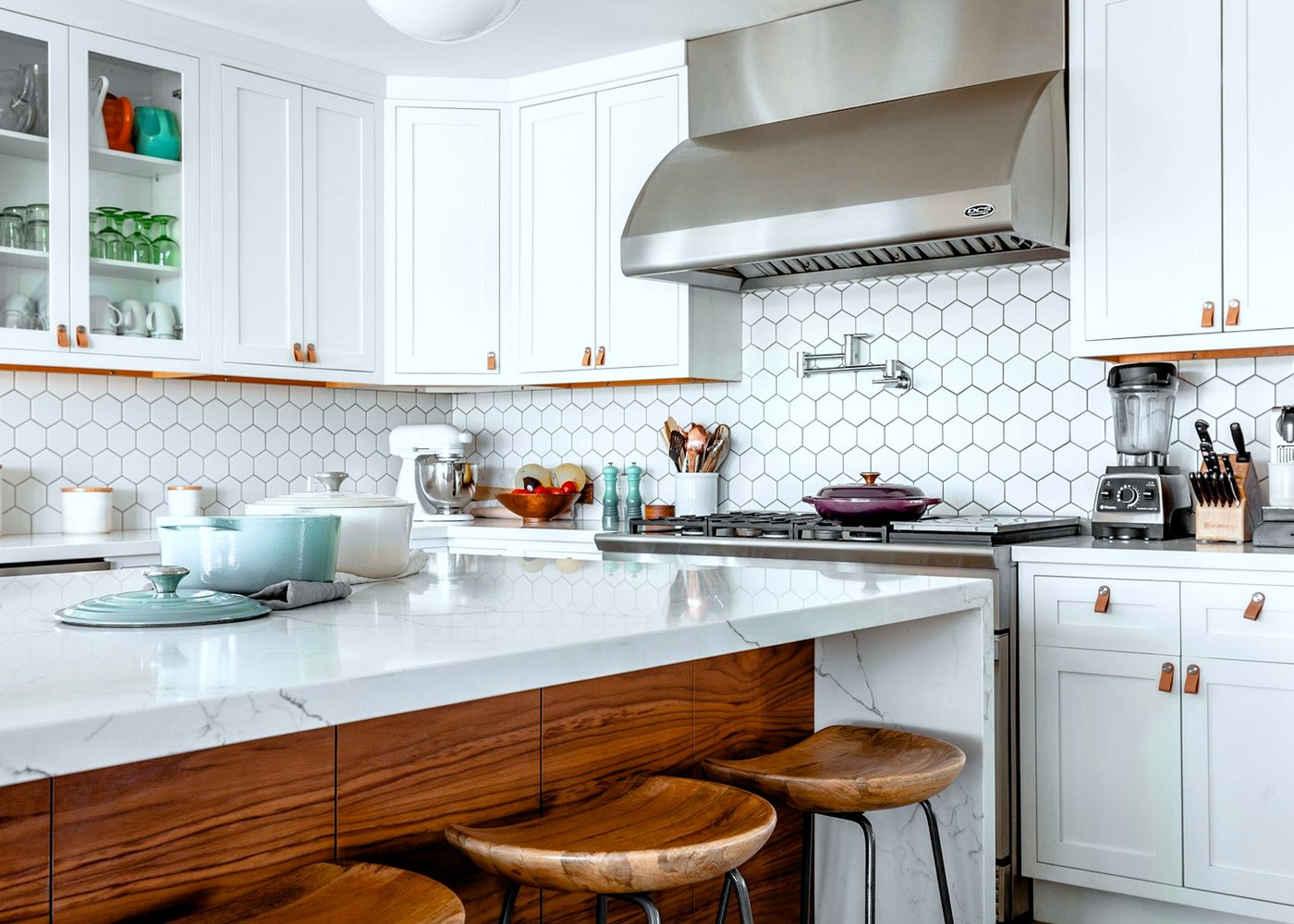 Clean domestic kitchen with white cabinets, a marble island and wooden stools